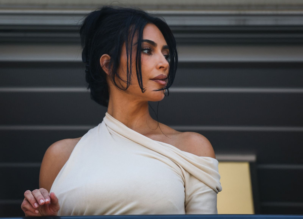 Kim Kardashian wears a oneshoulder dress and a claw clip hairstyle.